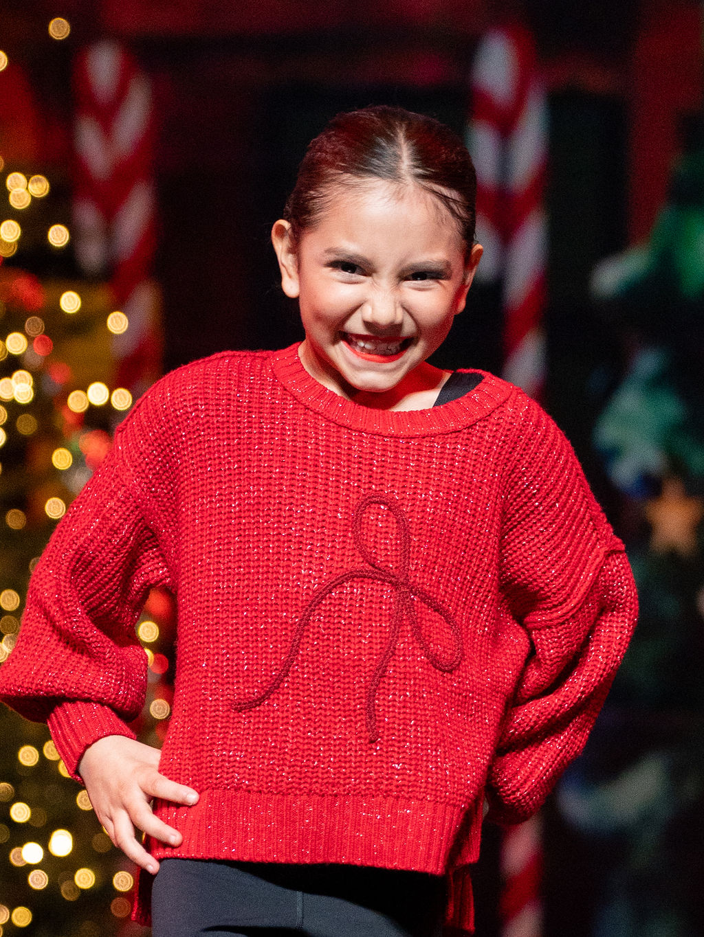 A young dancer beams in a red Christmas sweater on the Live to Give stage
